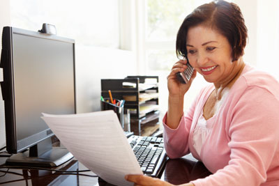 Woman in office talking on phone and reviewing paperwork